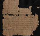 Broken parchment on black background Parchment is tan with faint black text. Letters are Greek.