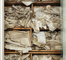 Picture of a closet with three wooden cases stuffed to overflowing with ancient charters. From the Grolier Club Library.