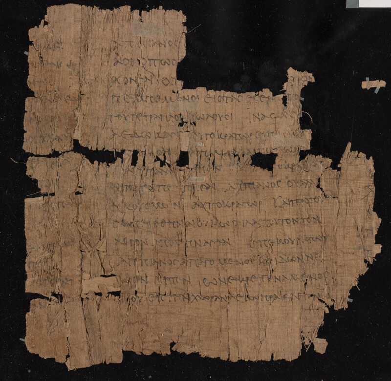 Broken parchment on black background Parchment is tan with faint black text. Letters are Greek.