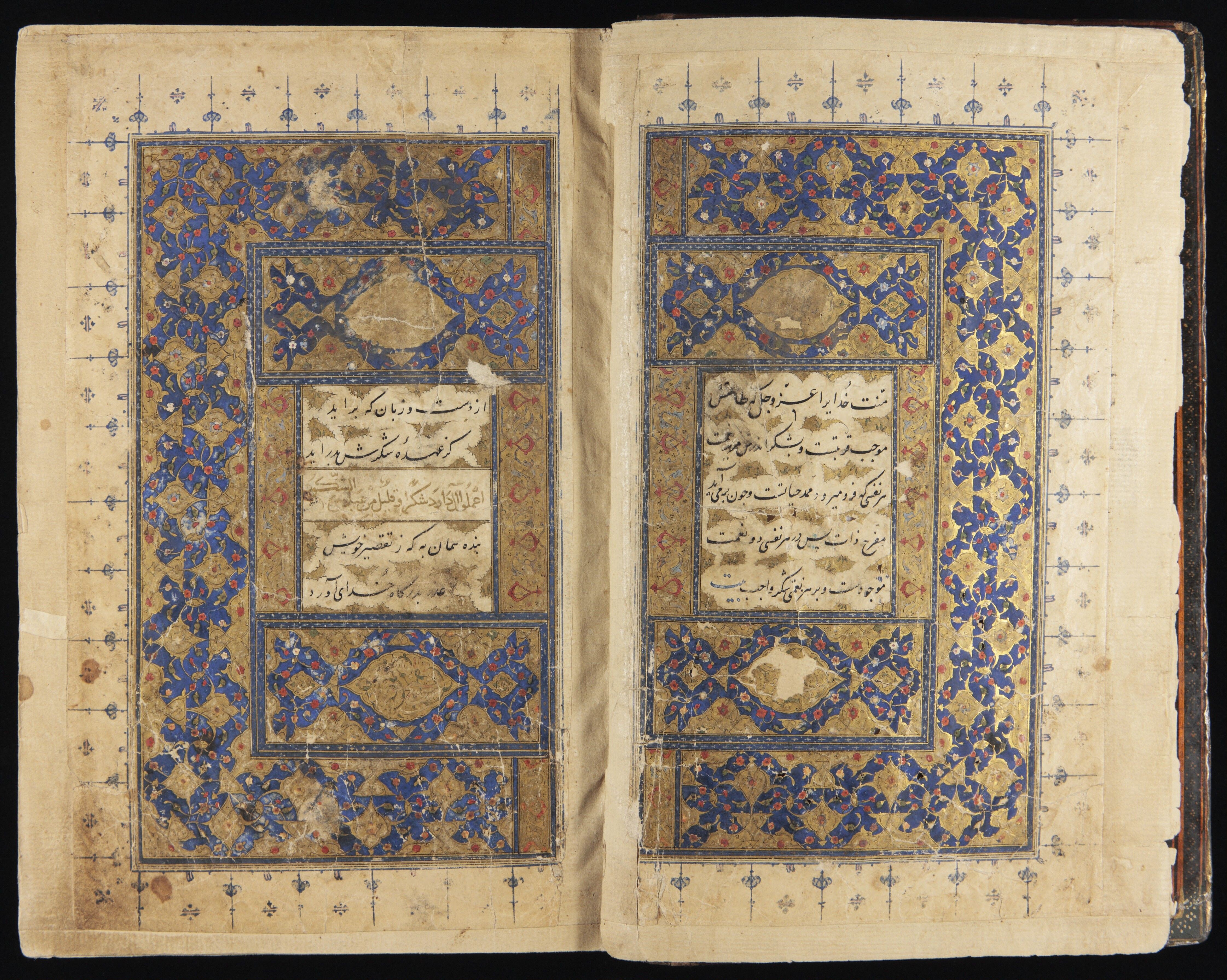 Persian MS 35. Image shows an opening of two facing pages early in the manuscript. These pages feature a small amount of caligraphic Persian surrounded by detailed borders worked in gold and deep blue.