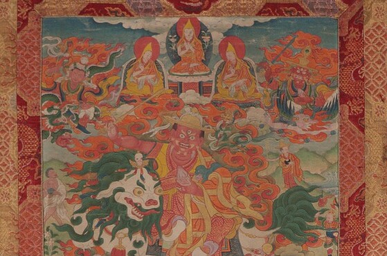 Tibet MSS 62, Box 24. Painting detail showing one large diety figure with three wide eyes at the center riding a lion. Five smaller figures float above him, the center three are robed in yellow and kneel on pillows. Flanking them to the right and left are two deity figures surrounded by deep orange flames. 