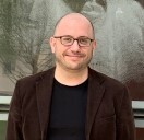 A man wearing glasses in front of a textured background